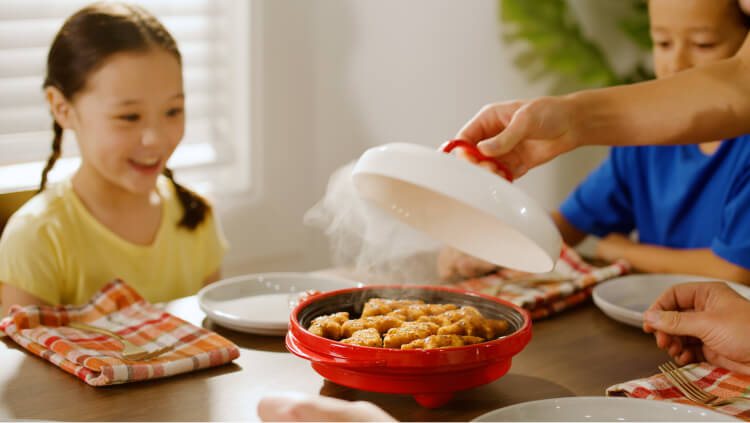 Rocket Chef Turbo Grill with its lid lifted, served at a family table